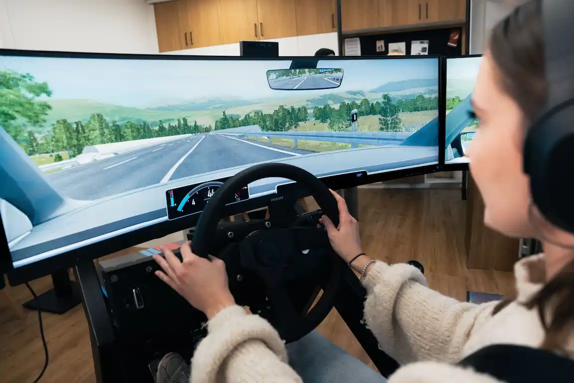 Fahrschülerin sitzt im modernen Fahrsimulator der Fahrschule Haas am Standort Würzburg und absolviert das erste Fahrtraining.