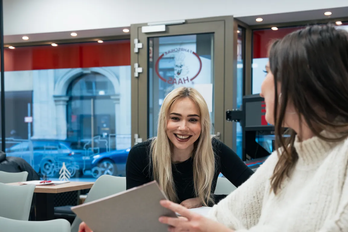 Fahrschülerinnen sitzen im Würzburger Standort der Fahrschule Haas, unterhalten sich und haben Spaß beim Fahrschulunterricht.
